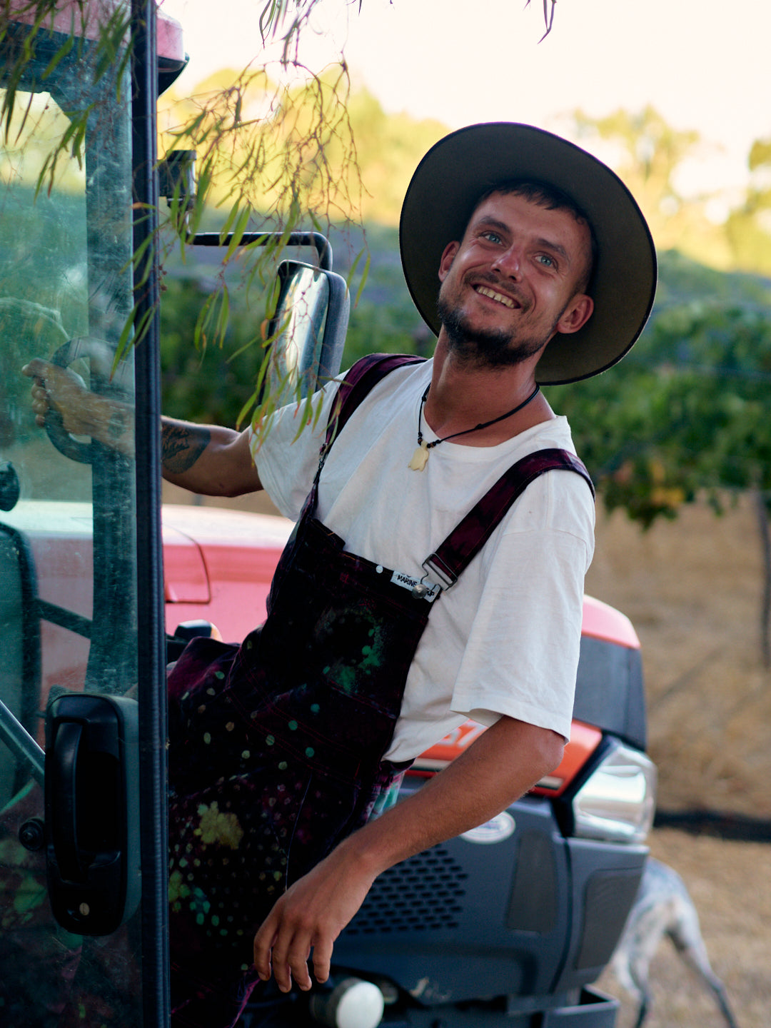 smiling farmhand on tractor wearing spotty overalls and akubra hat